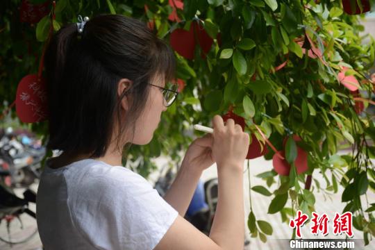 4月4日，江西理工大学生在心形卡纸上写下自己的家国心愿，将哀思与祝福一并挂在常青树上。曾江文 摄 曾江文 摄
